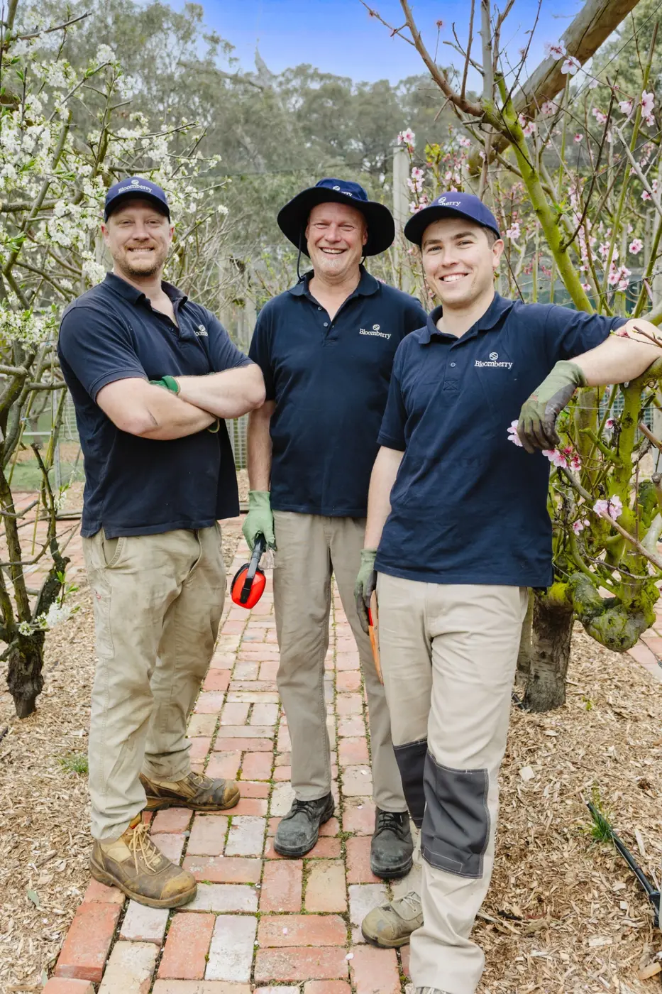 A Bloomberry landscaper standing beside the work ute in a leafy garden